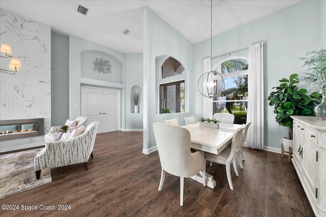 dining space with a premium fireplace, an inviting chandelier, and dark hardwood / wood-style flooring