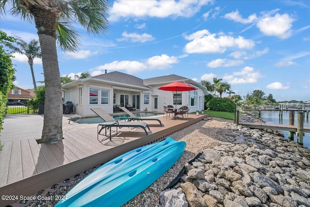 exterior space featuring a deck with water view, a patio area, and a dock