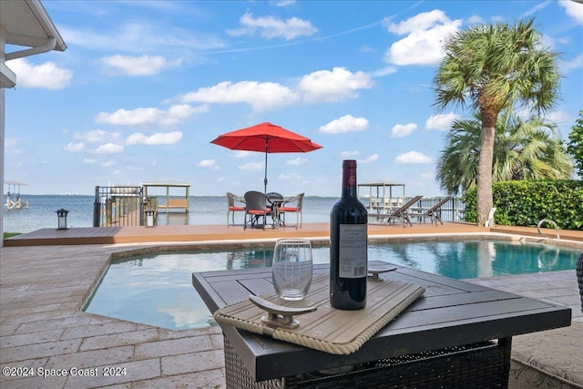 view of pool featuring a patio and a water view