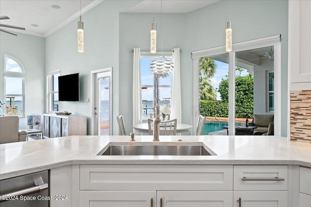 kitchen with hanging light fixtures, ceiling fan, white cabinetry, light stone countertops, and crown molding