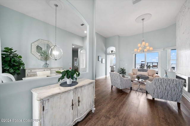 interior space featuring dark wood-type flooring, a notable chandelier, a towering ceiling, and pendant lighting