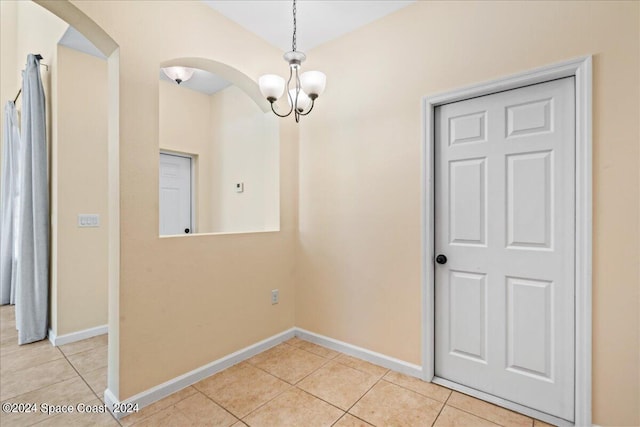 tiled empty room with a chandelier