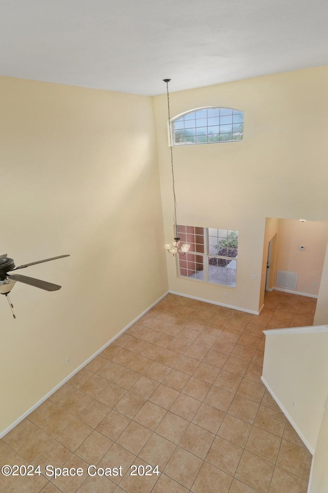 spare room featuring ceiling fan with notable chandelier