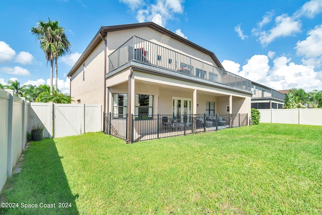 rear view of property with a balcony, a patio area, and a yard