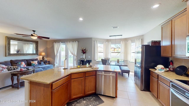 kitchen featuring ceiling fan, light tile patterned flooring, sink, appliances with stainless steel finishes, and a center island