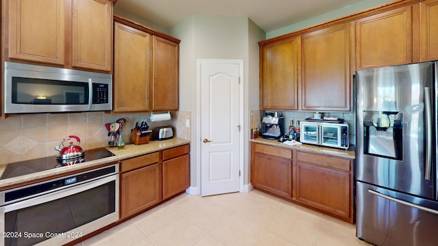 kitchen featuring light tile patterned flooring, appliances with stainless steel finishes, and backsplash