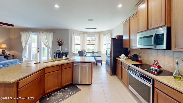 kitchen featuring tasteful backsplash, light tile patterned floors, black appliances, a kitchen island with sink, and sink