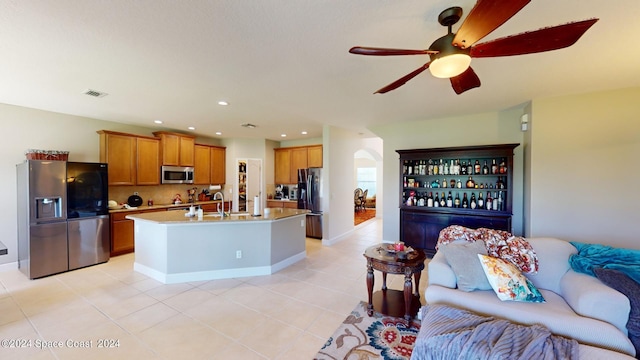 kitchen featuring sink, an island with sink, stainless steel appliances, light tile patterned floors, and ceiling fan