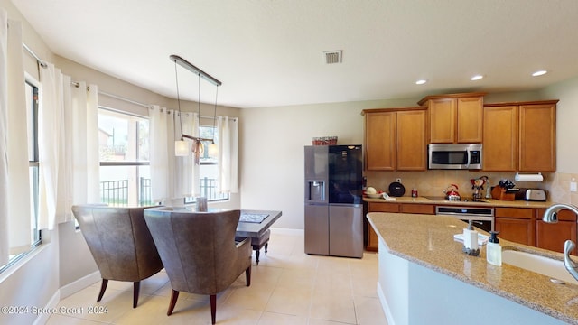 kitchen featuring light tile patterned flooring, sink, backsplash, appliances with stainless steel finishes, and decorative light fixtures