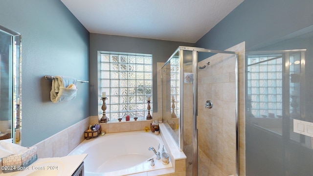 bathroom with a textured ceiling, shower with separate bathtub, and vanity