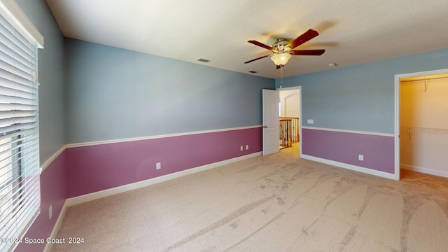 carpeted empty room with a wealth of natural light and ceiling fan