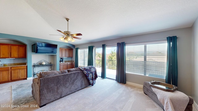 carpeted living room with a textured ceiling and ceiling fan