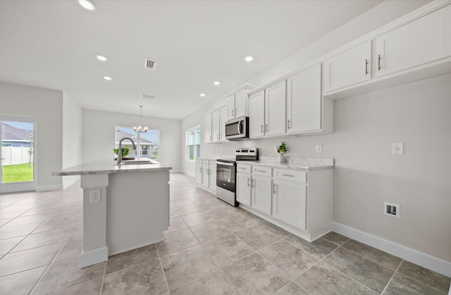 kitchen featuring stainless steel appliances, white cabinets, a center island with sink, and sink