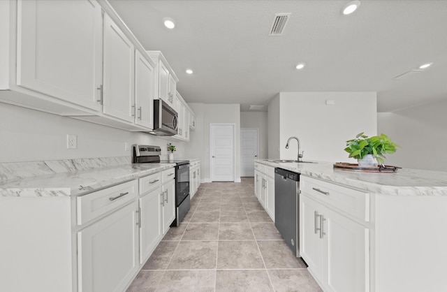 kitchen with sink, an island with sink, white cabinets, appliances with stainless steel finishes, and light tile patterned floors