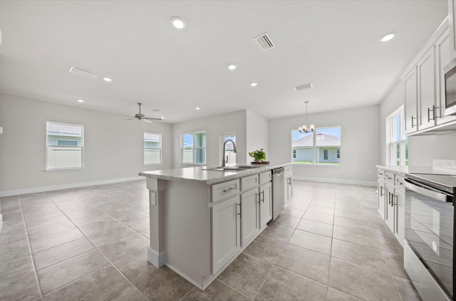 kitchen with sink, a center island with sink, stainless steel appliances, ceiling fan with notable chandelier, and a healthy amount of sunlight