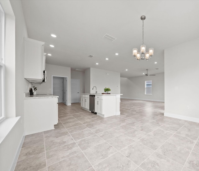 kitchen with an island with sink, white cabinets, ceiling fan with notable chandelier, appliances with stainless steel finishes, and decorative light fixtures