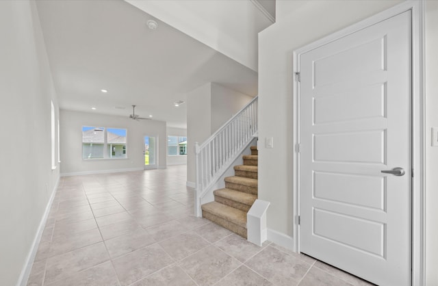 stairway featuring tile patterned flooring and ceiling fan