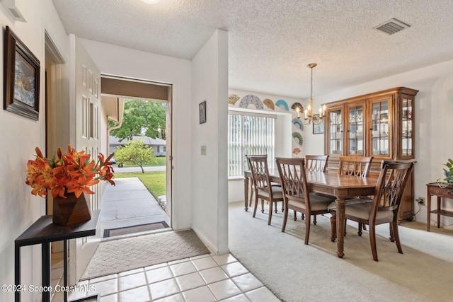 dining space featuring light carpet, a textured ceiling, and an inviting chandelier