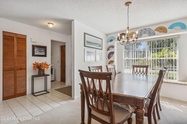 dining room with washer / clothes dryer, a textured ceiling, a chandelier, and light tile patterned flooring