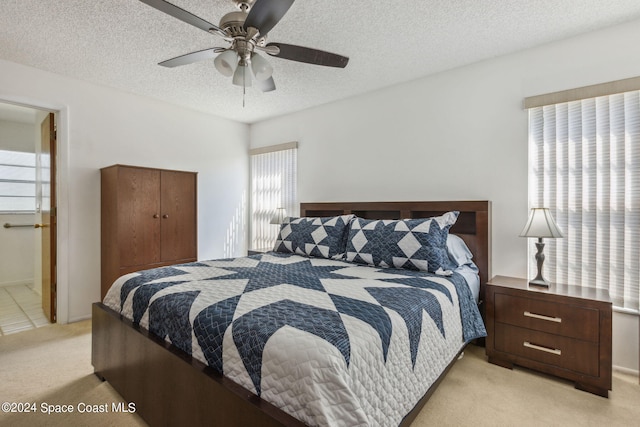 carpeted bedroom featuring ceiling fan, a textured ceiling, and ensuite bathroom