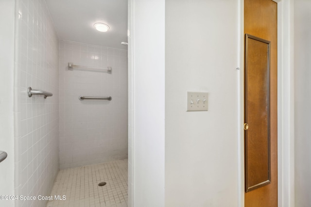 bathroom with a tile shower and tile patterned flooring