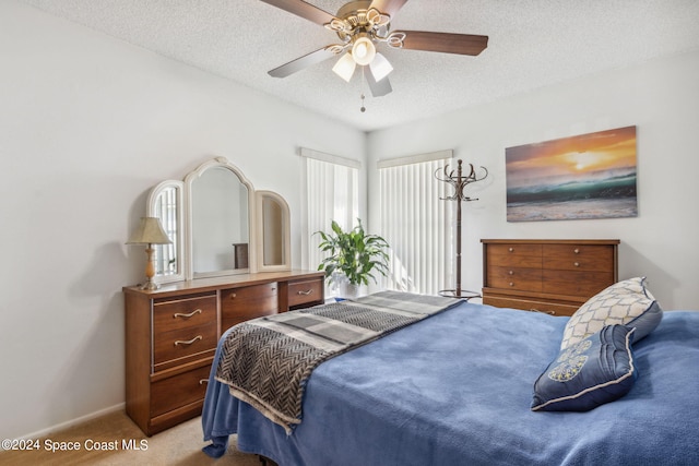 bedroom featuring ceiling fan, light colored carpet, and a textured ceiling