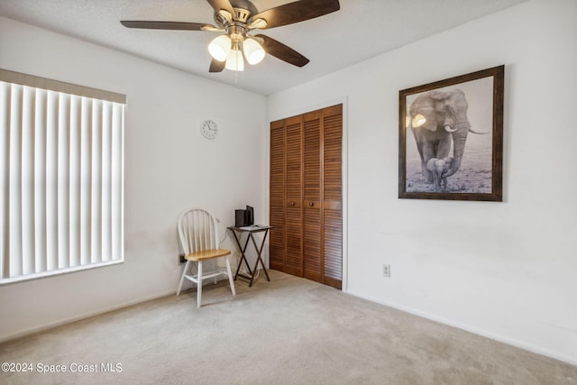 living area with ceiling fan and carpet