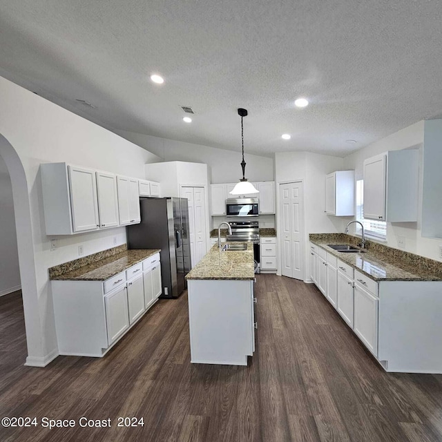 kitchen featuring appliances with stainless steel finishes, hanging light fixtures, white cabinetry, an island with sink, and dark hardwood / wood-style floors