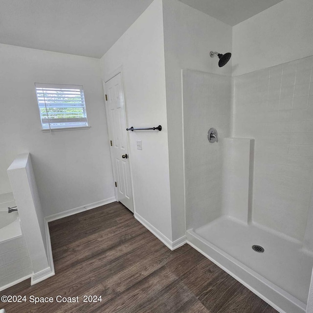 bathroom with a tile shower and hardwood / wood-style floors