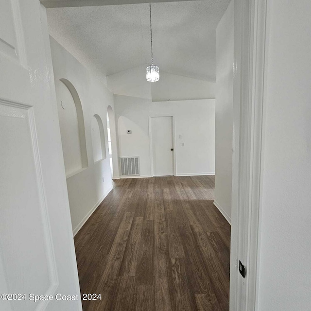 hall with vaulted ceiling, a textured ceiling, and dark hardwood / wood-style floors