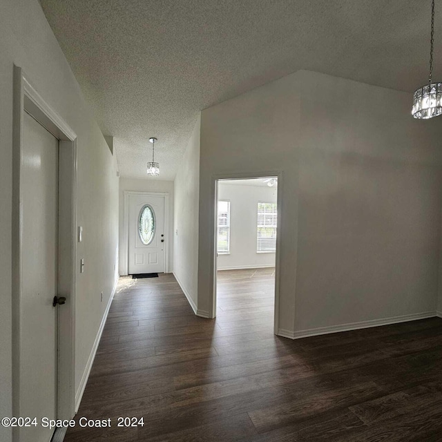 entrance foyer with a textured ceiling, dark hardwood / wood-style floors, and a chandelier