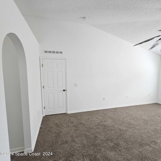 carpeted spare room with vaulted ceiling, ceiling fan, and a textured ceiling