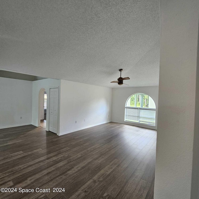 empty room with ceiling fan, a textured ceiling, and dark wood-type flooring