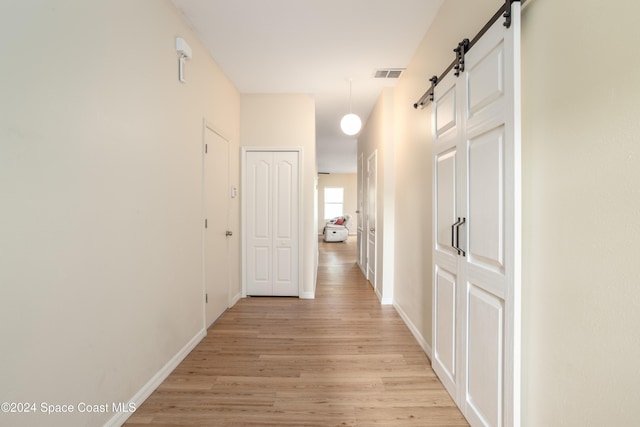 corridor featuring a barn door and light wood-type flooring