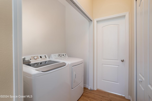 laundry area featuring washer and clothes dryer and light hardwood / wood-style floors