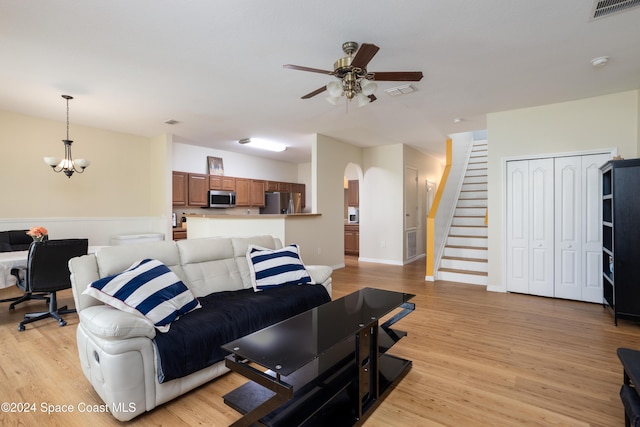 living room with light hardwood / wood-style floors and ceiling fan with notable chandelier