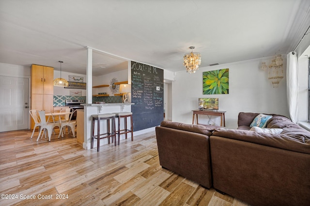 living room featuring an inviting chandelier, light wood-type flooring, and crown molding