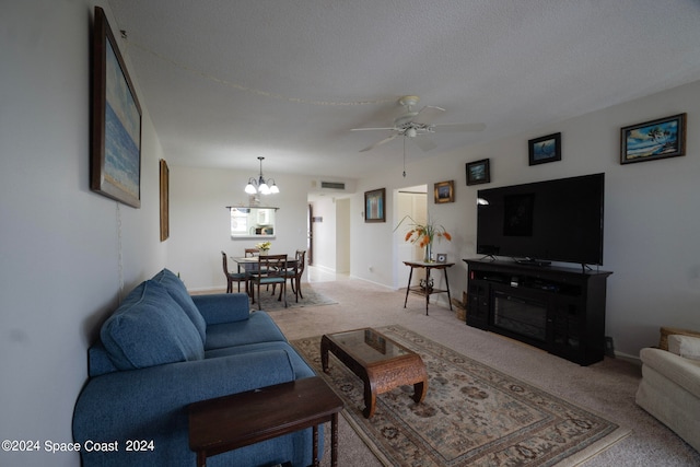 carpeted living room with ceiling fan with notable chandelier and a textured ceiling