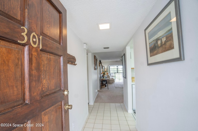 corridor featuring light tile patterned floors and a textured ceiling