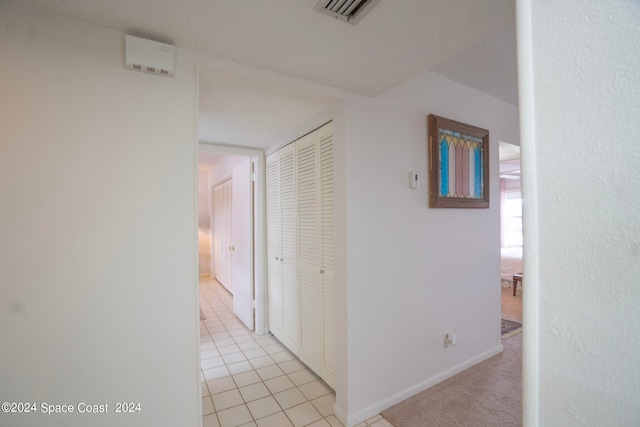 corridor featuring light tile patterned flooring and a textured ceiling