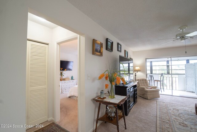 hallway with a textured ceiling and carpet flooring