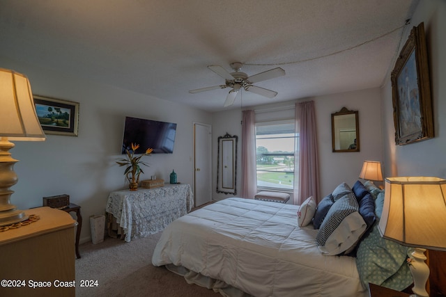 bedroom featuring light colored carpet, a textured ceiling, and ceiling fan