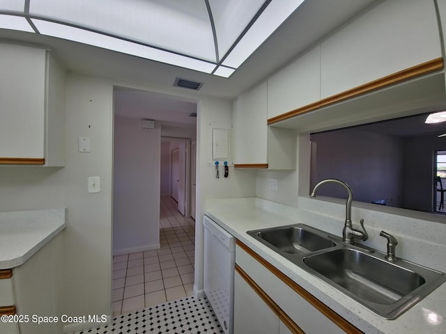 kitchen with light tile patterned floors, white cabinets, a sink, light countertops, and white dishwasher