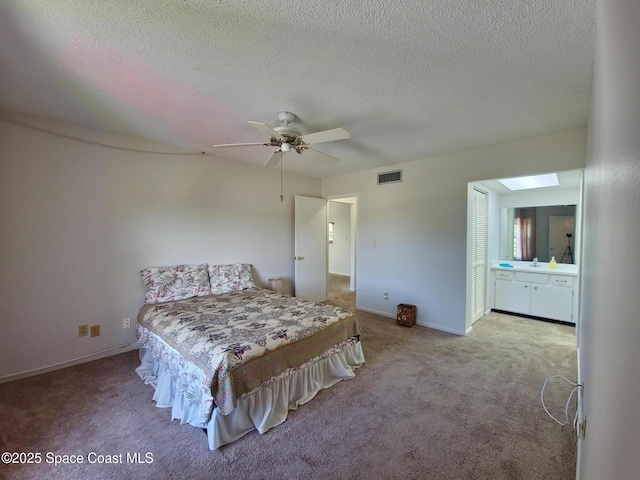carpeted bedroom with baseboards, a textured ceiling, connected bathroom, visible vents, and ceiling fan