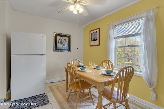 tiled dining area featuring ceiling fan and crown molding