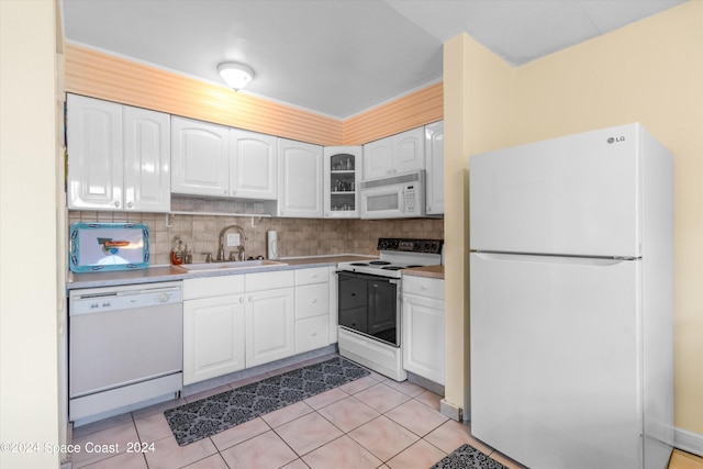 kitchen featuring decorative backsplash, white cabinetry, white appliances, light tile patterned floors, and sink