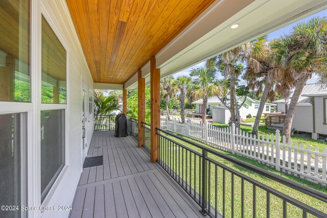 wooden deck with a porch and a lawn