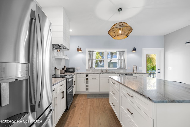 kitchen featuring hanging light fixtures, white cabinetry, stainless steel appliances, wood-type flooring, and sink