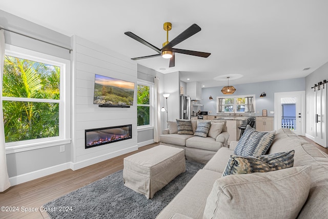 living room featuring ceiling fan, hardwood / wood-style flooring, and a large fireplace