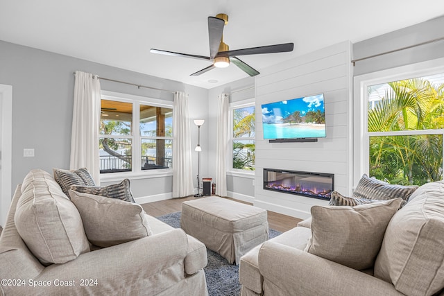 living room featuring ceiling fan, hardwood / wood-style flooring, a wealth of natural light, and a large fireplace